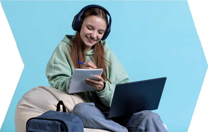 Estudiante feliz estudiando en línea, tomando notas y usando una computadora portátil.