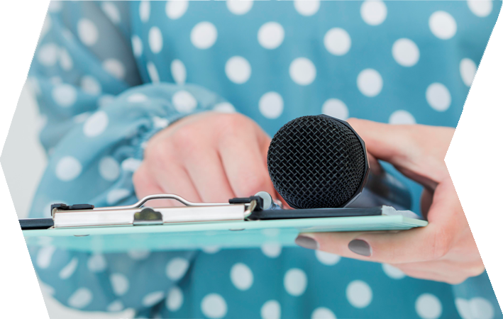 Primer plano de unas manos sosteniendo un micrófono y un portapapeles. Preparación de una rueda de prensa.
